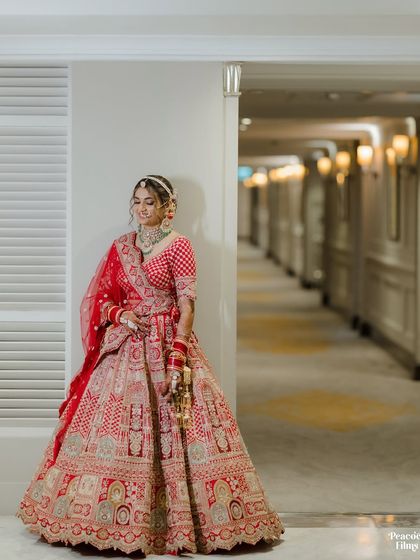 A full-length portrait of the bride in a hotel corridor, her elegant pose highlighting the beauty of her wedding lehenga.