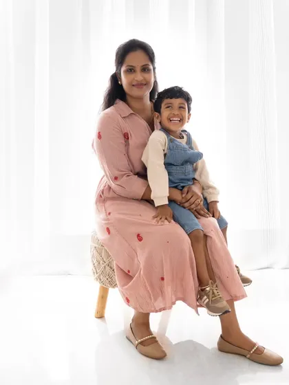 A lovely portrait of a mother and her smiling son. The coordinated pink outfits and the bright, clean background make for a beautiful and timeless photo.
