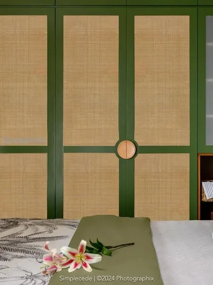 In the 'Cover me in Sunshine' master bedroom, we designed this wardrobe with green and rattan panels and custom circular wooden handles, continuing the room's earthy, serene character.