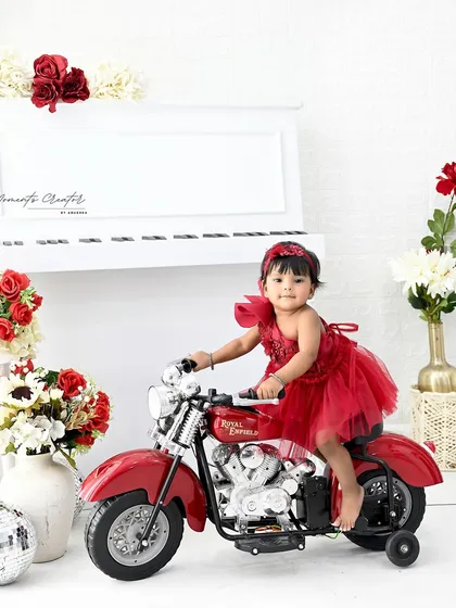 A little rider with big charm. This baby girl looks absolutely adorable and confident on her miniature Royal Enfield bike, making for a unique and memorable birthday photo.