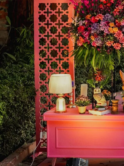 A styled corner featuring a pink desk, a large floral arrangement, and whimsical animal figurines. This setup serves as a beautiful and functional element, perhaps for guest favors or a welcome station.