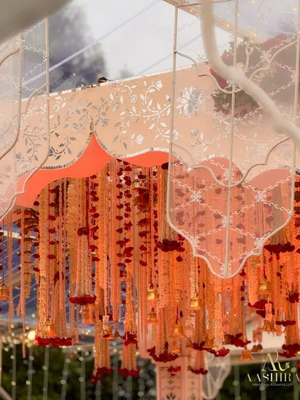 A close-up of the canopy, adorned with cascading strings of tuberose, red carnations, and tiny golden bells that chimed softly, adding a sensory detail to the sacred space.