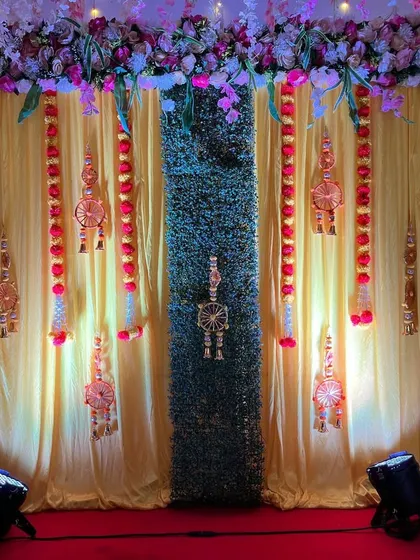 An elegant backdrop for a traditional function, featuring yellow drapes, a central green panel, and decorative hangings with marigold flowers.