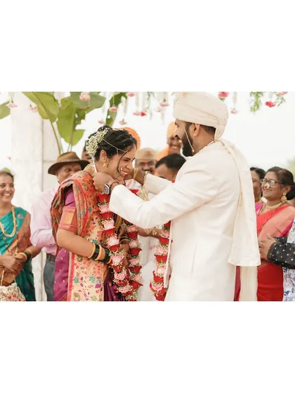 The joyful exchange of garlands, or Varmala. This candid shot captures the laughter and happiness of the couple and their families during this fun-filled ritual.
