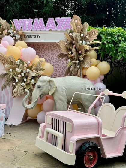 The 'Vismaya' marquee sign and pink jeep are key focal points in this unique pastel safari setup.
