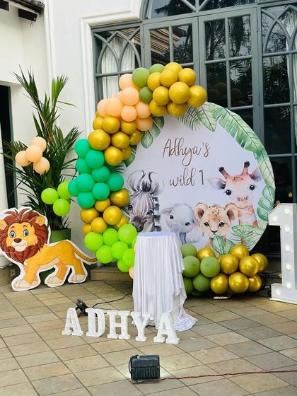 This is a duplicate of ID 63. A 'Wild One' jungle safari theme perfect for an outdoor first birthday. This decoration features a custom backdrop with cute safari animals, an organic balloon garland in green and gold, and character cutouts.