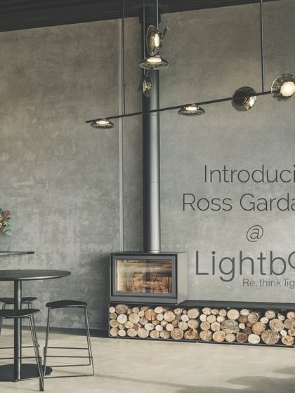 An introductory image for Ross Gardam at Lightbox, featuring the Ceto chandelier in a rustic-modern interior with a fireplace.