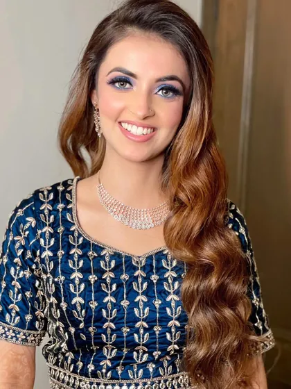 A close-up of this bold and beautiful reception look. The vibrant blue eyeshadow makes her eyes pop, balanced with a dewy base and a soft pink lip for a striking finish.