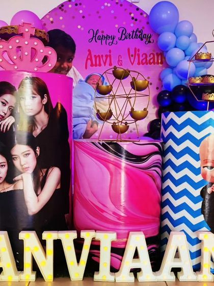 A close-up of a joint K-Pop and Boss Baby-themed setup, showing the custom-printed plinths and 'ANVIAAN' marquee letters.