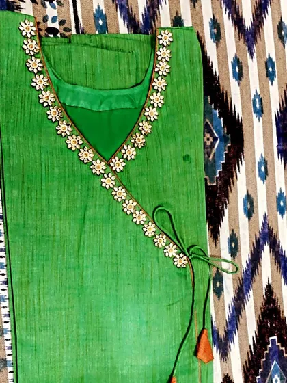 This green kurta features a beautiful V-neckline adorned with flower-shaped lace and a side tie-up with tassels.