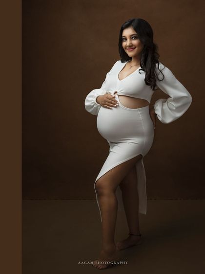 A full-length view of the stylish white dress, its modern design beautifully highlighting the baby bump.