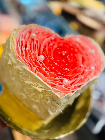 A special heart-shaped cake with a delicate rose petal effect, designed for a wife's birthday. The intricate piping and pearl details create a beautiful and romantic centerpiece for any celebration of love.
