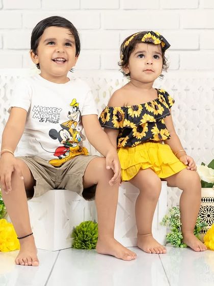 A charming portrait of a brother and sister sitting together. Their coordinated yellow and black outfits are stylish and fun for a kids' photoshoot.