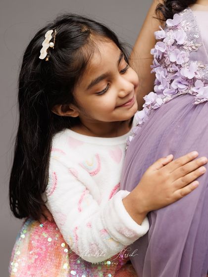 A tender moment between a big sister-to-be and her mother's baby bump. Her gentle smile shows all the love she already has for her new sibling.