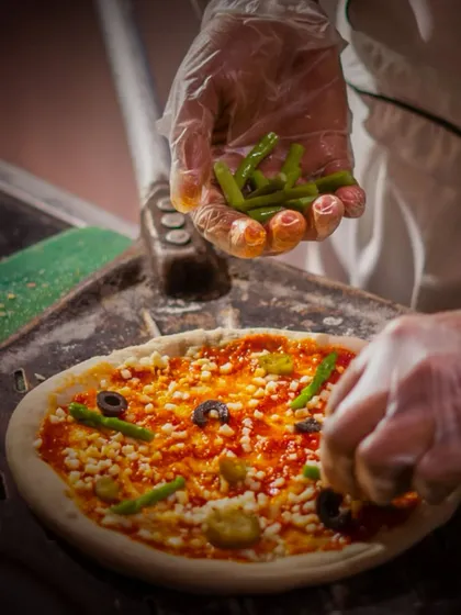 A chef carefully adds fresh asparagus to a pizza before it heads into the oven. We use only the freshest ingredients at our live stations to ensure the highest quality.
