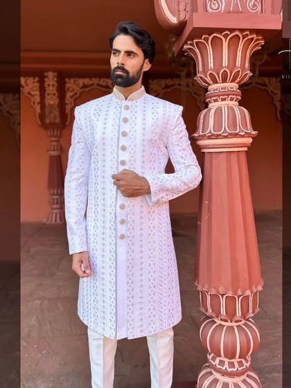 A three-quarter view of the white and gold embroidered sherwani.