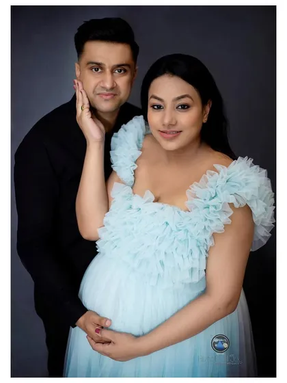 This is a classic couple's maternity portrait, capturing the quiet love and anticipation between partners. The soft blue gown and the simple, loving pose create a timeless and elegant image that they will cherish forever.