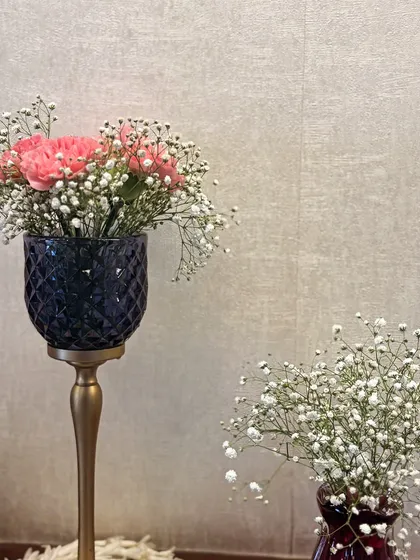I use a variety of vases and stands to create arrangements with different heights and textures. This combination of pink carnations in a dark goblet and baby's breath in a smaller vase is a great example of creating visual interest.