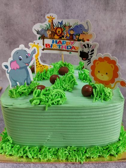Go on a sweet safari with this jungle themed birthday cake. It's decorated with green frosting to look like grass and features cute, edible toppers of jungle animals like a lion, elephant, and giraffe.
