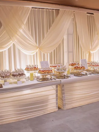 An exquisite dessert table setup for a corporate anniversary, featuring illuminated tables and elegant draping, making the sweets a part of the decor.