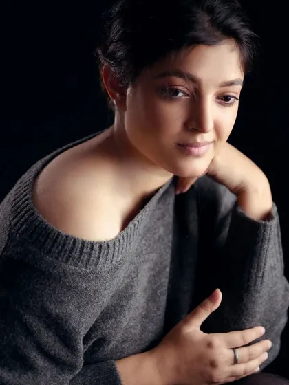 This portrait showcases a pensive and gentle mood. The off-the-shoulder sweater and soft lighting create a feeling of quiet confidence and natural beauty.