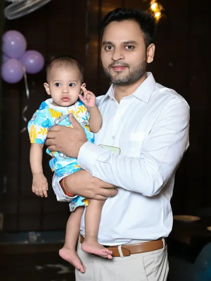 A father holds his baby boy, both looking towards the camera. This is a simple, clean portrait that highlights the connection between them.