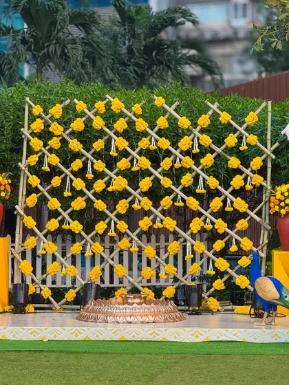 We love the classic sunshine vibe of a Haldi ceremony. Here, a custom bamboo lattice backdrop adorned with bright yellow marigolds and traditional hanging tassels creates a joyful and picture-perfect setting for the celebration.