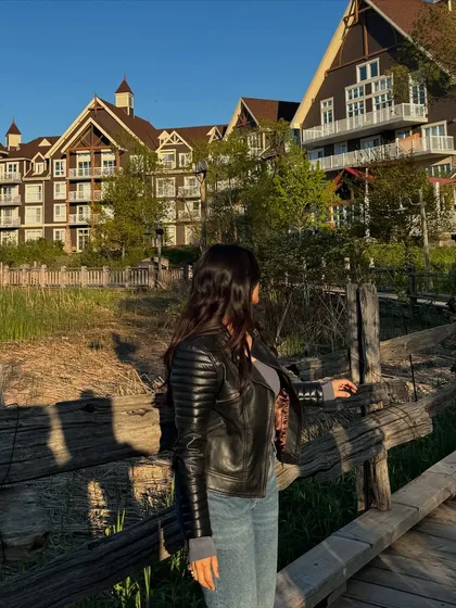 A shot from behind at Blue Mountain, focusing on the texture of the leather jacket and the beautiful resort background during golden hour.