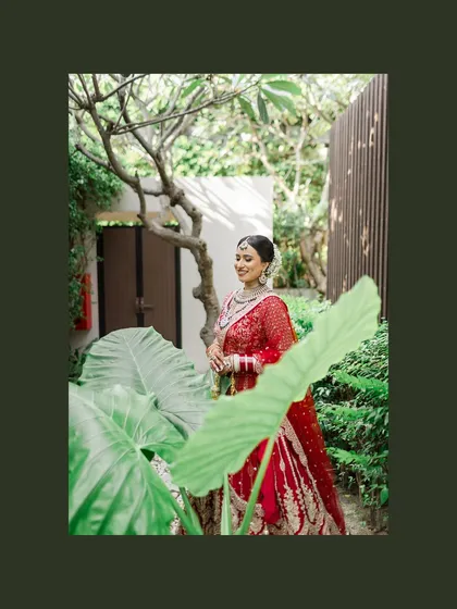 A beautiful bridal portrait, with the bride framed by lush green leaves. This artistic composition adds a touch of nature and artistry to her photo.