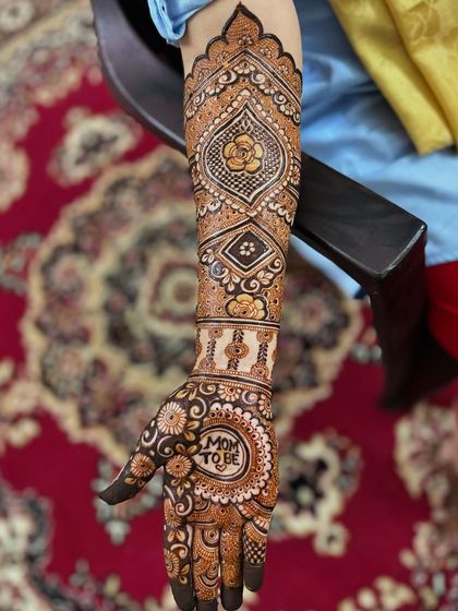 A side view of the "Mom to be" mehendi, showing how the personalized element is the centerpiece of the palm design.
