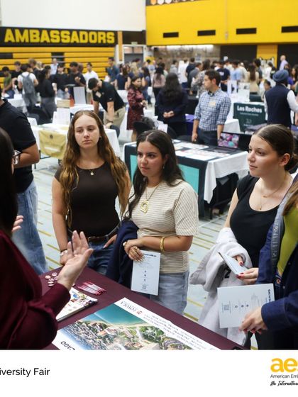 A group of students listens intently to a university representative. These small group interactions allow for specific questions about program details, campus life, and application requirements.