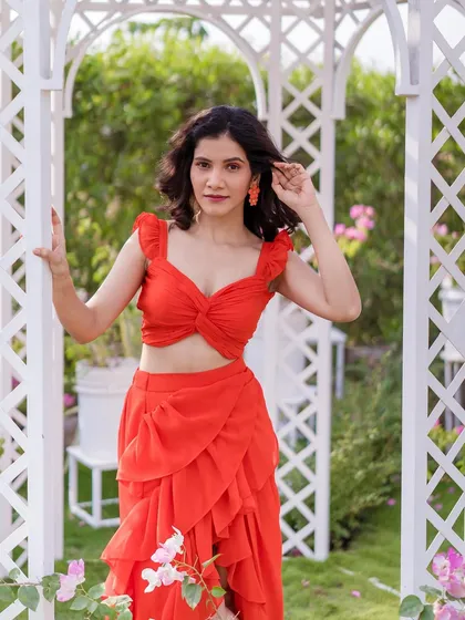 A close-up of the model in the red co-ord set, highlighting the playful design of the ruffled top.