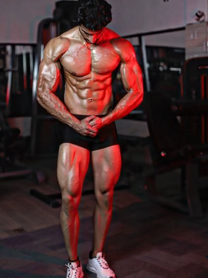A powerful most muscular pose under red lighting, showcasing full-body conditioning.