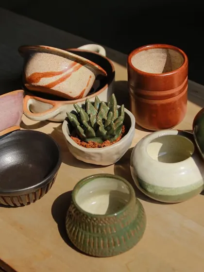 A charming collection of small bowls, planters, and cups, showcasing the students' exploration of both form and function.