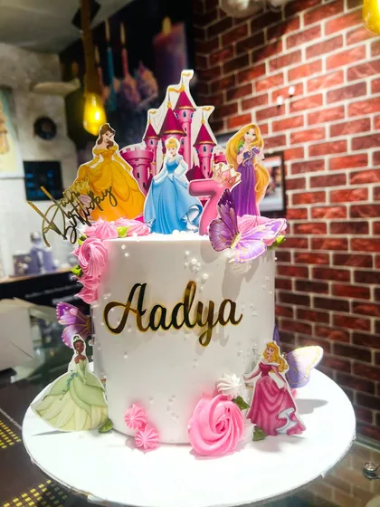 A Disney princess dream cake for Aadya's 7th birthday, featuring Cinderella, Belle, Rapunzel, and Tiana around a castle topper.