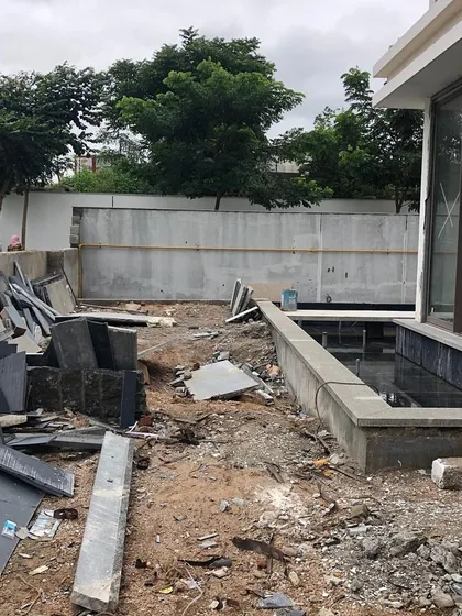 A construction site with piles of stone and rubble. This image is part of the "before" story, showing the raw materials and challenges that are overcome to create a polished, serene garden.