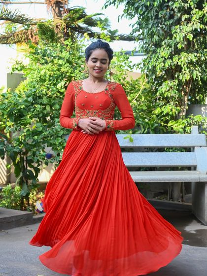 My enchanting client Nisarga looks stunning in this vibrant orange gown. I designed it with a flowing pleated skirt and an intricately embroidered bodice, creating a look of timeless elegance for her special event.