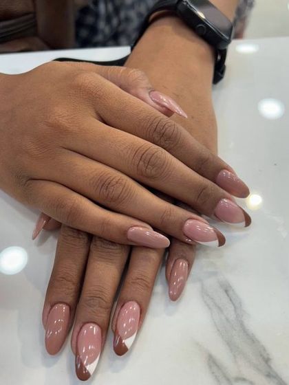 A unique, abstract French manicure on almond nails, using a nude base with brown and white curved tips for a modern, artistic style.
