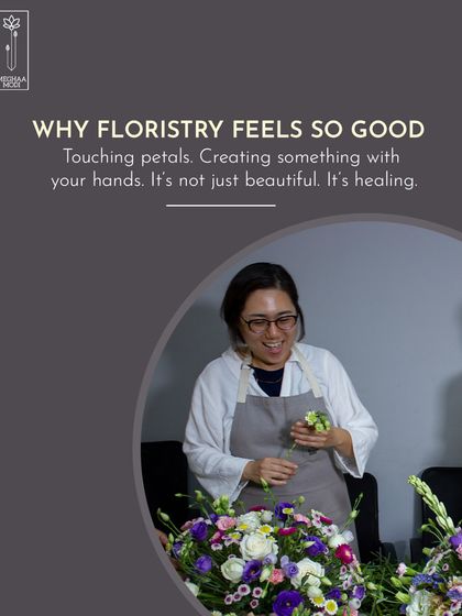 The simple, healing act of working with your hands. A student smiles as she puts the finishing touches on her arrangement, showcasing the joy that comes from creating something beautiful.