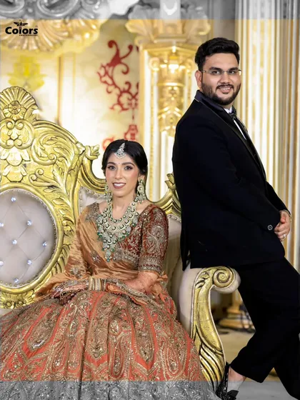 A regal portrait of the couple on an ornate golden throne at their reception. This shot has a touch of royal elegance.