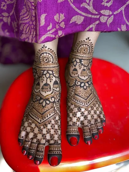 A clear view of the intricate bridal foot mehandi, showing the detail in the check patterns and jhumka motifs.