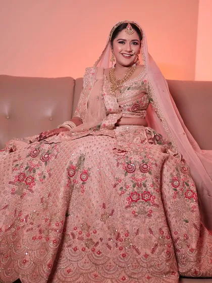 A full portrait of the bride in her pastel pink lehenga. The soft glam makeup completes this dreamy and elegant look.