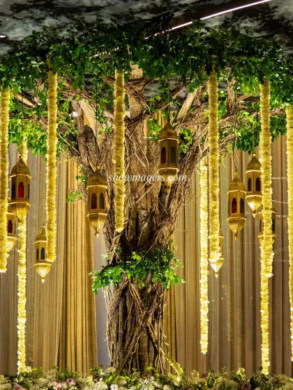 A close-up of the 'tree of life' installation, showing the intricate details of the trunk, hanging lanterns, and floral strings.