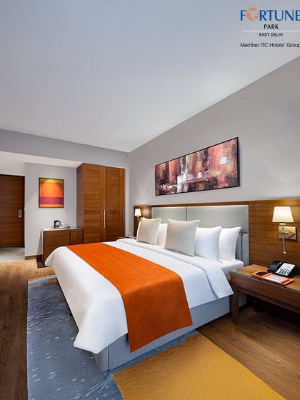 Our luxury room with warm orange accents offers a vibrant yet cosy atmosphere. The room is furnished with a king-sized bed, modern art, and soft lighting.