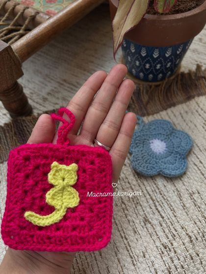 This small pink pouch with a cute cat appliqué is perfect for holding earpods or other small items. It can also be used as a charming bag charm.