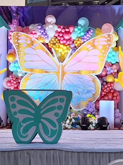 A close-up of our custom-fabricated props for a butterfly-themed birthday. This photo highlights the detailed butterfly-shaped table and the large, golden butterfly backdrop, both made in our workshop.