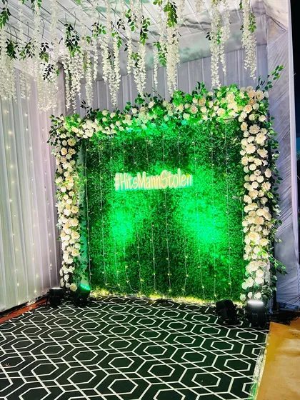 The green wall photo booth, with its bright neon sign, creates a striking contrast and a perfect backdrop for evening photos.