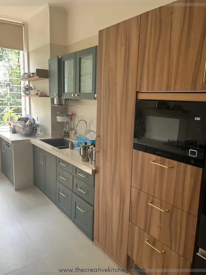 A closer look at the seamless integration of appliances within our custom cabinetry. The warm wood grain of the tall unit beautifully complements the deep green of the lower cabinets, showcasing our attention to material harmony.