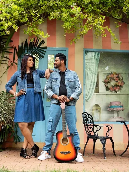 A fun and casual shot of a couple with a guitar in front of a charming, vine-covered house facade.