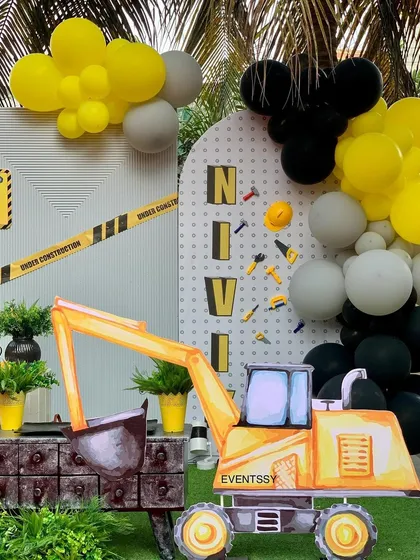 A personalized backdrop with the birthday boy's name and a large digger prop, perfect for photos.